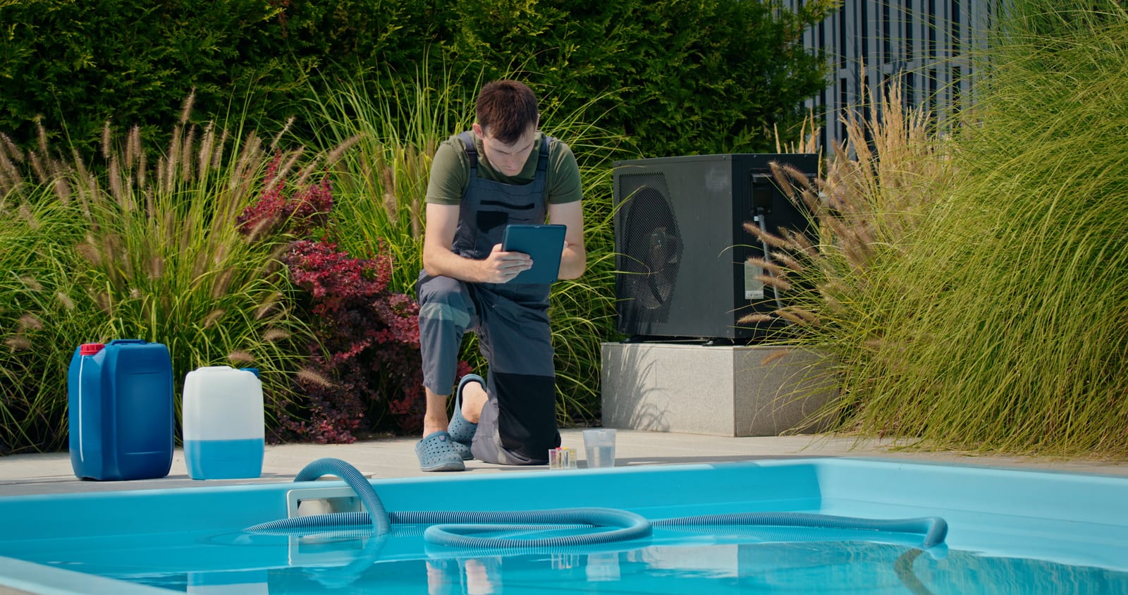 Pool service business technician reviewing route data on a tablet beside a residential pool