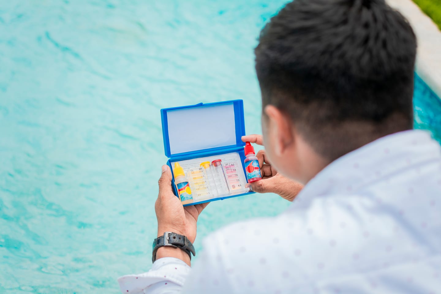 Training for a pool service business: technician reading a pH and chlorine test kit beside a residential pool
